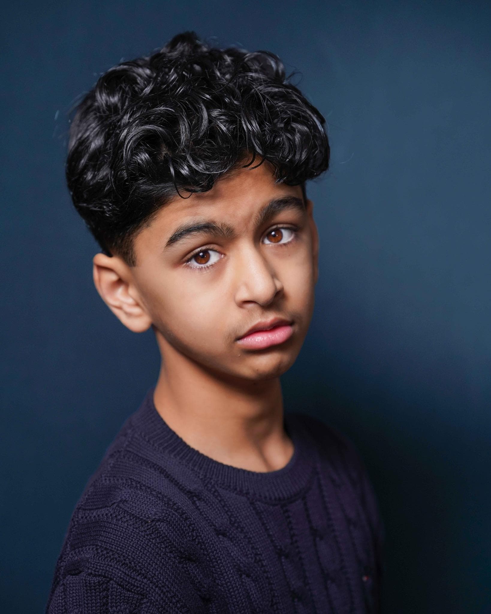 Tanay Joshi studio headshot with curly hair and dark sweater
